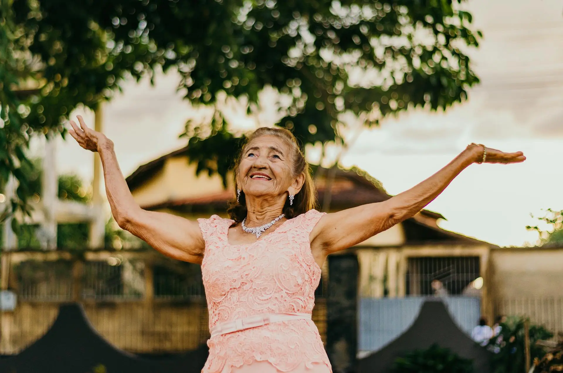 une dame senior qui lève les bras en regardant le ciel